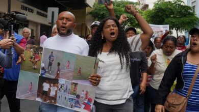 Luis Arroyo, a la izquierda, con las fotos de sus dos hijos desaparecidos, Ismael y Josué, quienes fueron detenidos por militares el 8 de diciembre. (AP Foto/César Muñoz)