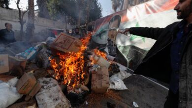 Una imagen del derrocado sirio Bashar al Assad arde en el fuego mientras un miembro sirio de las fuerzas rebeldes destruye drogas y bebidas alcohólicas encontradas en un edificio en Damasco (AP Foto/Omar Sanadiki)