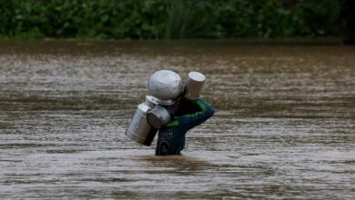 Un residente lleva cubos de leche mientras cruza una carretera inundada. Foto: Reuters