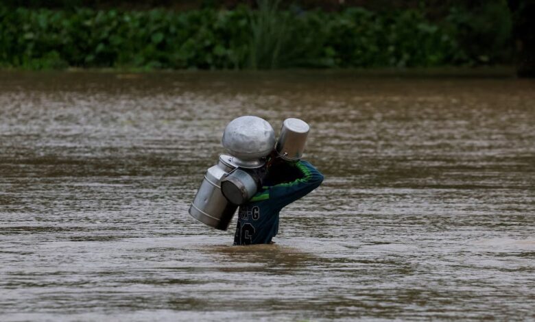 Un residente lleva cubos de leche mientras cruza una carretera inundada. Foto: Reuters