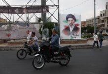 Varias personas circulan cerca de una pancarta con la imagen del líder supremo de Irán, Mojtaba Khamenei, en una calle de Teherán, Irán.