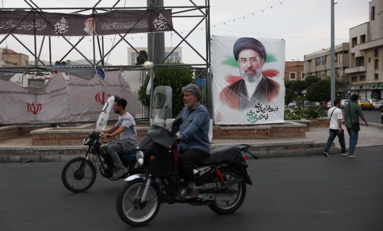 Varias personas circulan cerca de una pancarta con la imagen del líder supremo de Irán, Mojtaba Khamenei, en una calle de Teherán, Irán.
