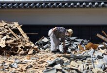Una persona retira escombros de una puerta derrumbada en un templo a causa de un terremoto de magnitud 7,1 que sacudió la prefectura de Kumamoto, en el sur de Japón
