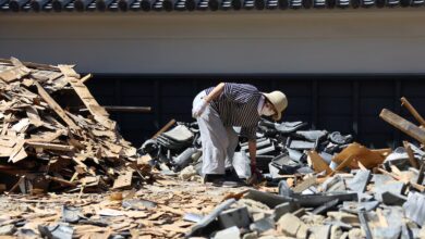 Una persona retira escombros de una puerta derrumbada en un templo a causa de un terremoto de magnitud 7,1 que sacudió la prefectura de Kumamoto, en el sur de Japón