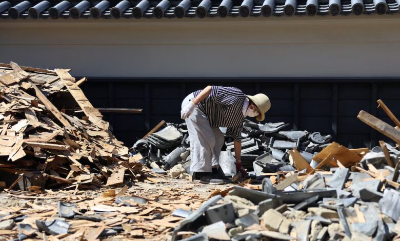 Una persona retira escombros de una puerta derrumbada en un templo a causa de un terremoto de magnitud 7,1 que sacudió la prefectura de Kumamoto, en el sur de Japón